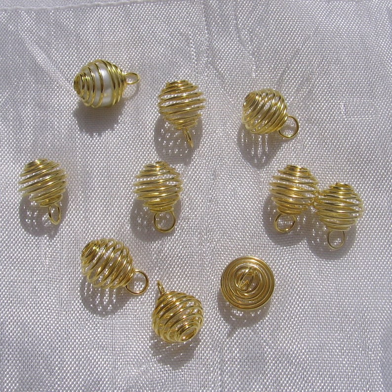 May include: Ten gold wire cage pendants, one of which contains a single white pearl. The cages are all closed and have a small loop at the top for hanging.