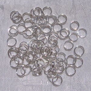 May include: A large pile of silver jump rings. The rings are all the same size and are arranged in a random pattern.