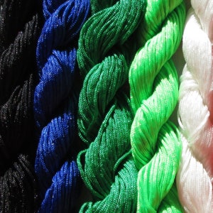 May include: Close-up of five spools of colorful cord. The cords are black, blue, green, lime green, and white. The cords are twisted and arranged in a vertical row.