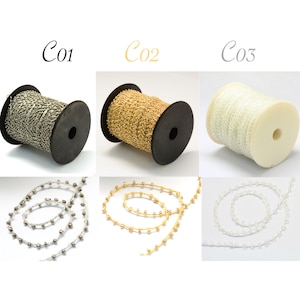 Puede incluir: Tres carretes de cadena con cuentas, uno plateado, uno dorado y uno blanco. Los carretes están etiquetados como C01, C02 y C03.
