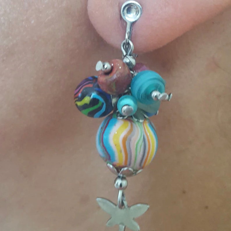 May include: A pair of dangle earrings with a silver star charm and a cluster of colorful beads. The beads are blue, green, red, and black.