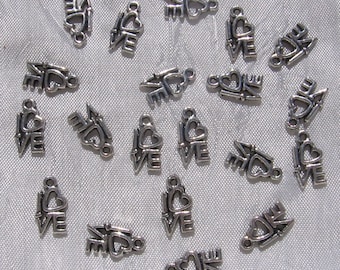May include: A collection of silver-toned metal charms featuring the word "love" with a heart and arrow design.