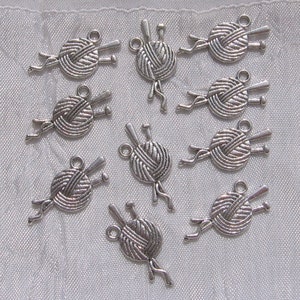 May include: Ten silver charms shaped like balls of yarn with knitting needles. The charms are ideal for jewellery making or scrapbooking.