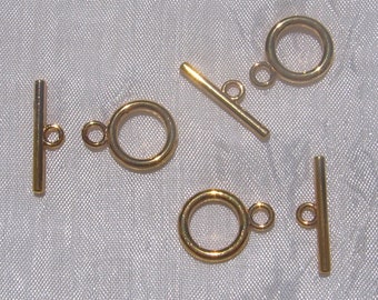 May include: Five gold-toned metal toggle clasps for jewelry making. Each clasp has a round ring and a straight bar.