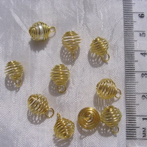 May include: Ten gold wire cage pendants, one of which contains a single white pearl. The cages are approximately 2.5 cm in diameter and have a loop at the top for hanging.