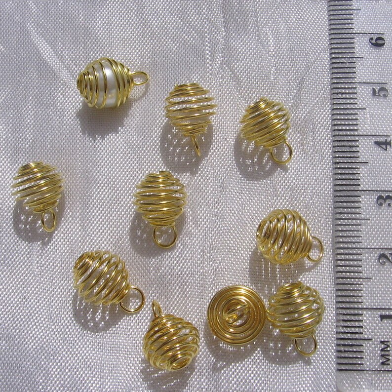 May include: Ten gold wire cage pendants, one of which contains a single white pearl. The cages are approximately 2.5 cm in diameter and have a loop at the top for hanging.