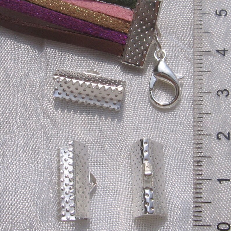 以下が含まれることがあります： ジュエリー作りのためのシルバーメタルクラスプ。クラスプの長さは約2.5cmで、表面はテクスチャ加工されています。シルバーメタルのロブスタークラスプもあります。