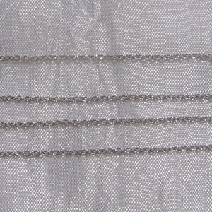 Può includere: Primo piano di quattro delicate collane a catena color argento. Le catene sono composte da piccole maglie circolari spaziate uniformemente. Lo sfondo è un tessuto strutturato di colore chiaro, che fornisce un sottile contrasto con le catene lucenti. Le catene sono parallele.