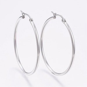 May include: A pair of silver hoop earrings. The earrings are simple and elegant, with a smooth, polished finish.