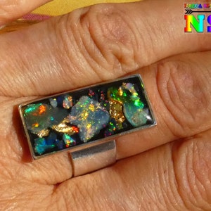 Peut inclure: Une bague en argent avec un sertissage rectangulaire noir rempli d'opale irisée et de paillettes d'or.