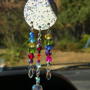 Può includere: Un ciondolo rotondo bianco per auto con glitter e un arcobaleno di perline di cristallo che pendono.