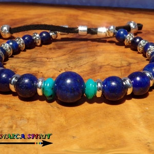 Peut inclure: Un bracelet composé de perles de lapis-lazuli bleu foncé et de turquoise, séparées par des entretoises en métal argenté. Le bracelet est monté sur un cordon noir et possède une fermeture réglable. Le logo Atelier Nazca Spirit est visible.