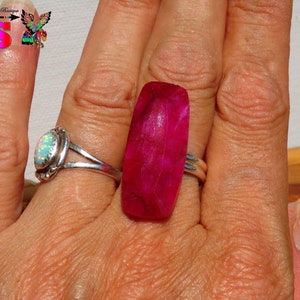 Peut inclure: Une bague en argent avec une pierre précieuse rose. La bague est sur le doigt d'une personne.