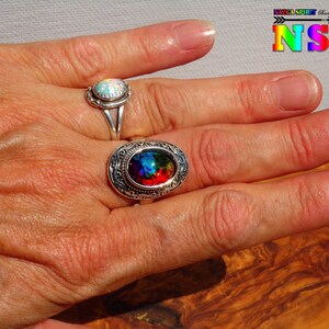 Pode incluir: Duas alianças de prata com pedras preciosas de forma oval. A aliança à esquerda tem uma pedra de opala branca. A aliança à direita tem uma pedra preciosa iridescente multicolorida.