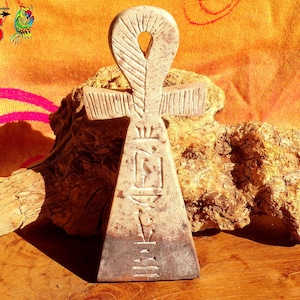 Può includere: Un simbolo Ankh in ceramica bianca con intagli intricati. L'Ankh è un simbolo di vita e immortalità nella cultura dell'antico Egitto.