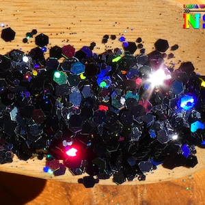 Peut inclure: Paillettes noires irisées avec une finition holographique. Les paillettes sont dans une petite cuillère en bois.