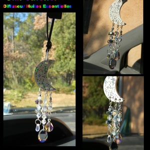 Peut inclure: Un charme de voiture en forme de croissant de lune blanc avec des paillettes argentées et un prisme de cristal suspendu. Le charme est suspendu à une ficelle noire et est attaché à un rétroviseur. Le texte "Sun Catcher Diffuseur Huiles Essentielles" est visible en haut de l'image.