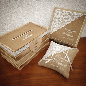 Peut inclure: Un ensemble de décoration de mariage rustique avec une boîte en bois avec un couvercle en toile de jute et une bordure en dentelle, un coussin en toile de jute avec une bordure en dentelle et les mots "Angelique et Raphael 8 août 2020" brodés dessus, et une pancarte en toile de jute avec une bordure en dentelle et les mots "Angelique et Raphael 8 août 2020" brodés dessus.