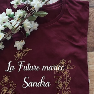 May include: Burgundy t-shirt with a gold floral design and the text "La Future mariée Sandra le 15 mai 2024".