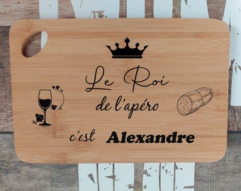 May include: A wooden cutting board with a crown, a glass of wine, a sausage, and the text "Le Roi de l'apéro c'est Alexandre".