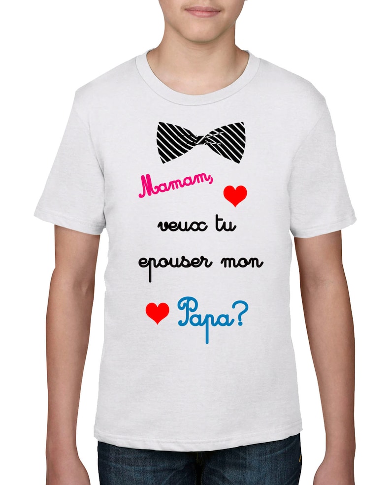 May include: White t-shirt with a black bow tie graphic and the text "Maman, veux tu epouser mon Papa?" in pink, black, red, and blue. Features two red hearts.