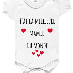 Peut inclure: Combinaison blanche pour bébé avec un texte noir qui dit "J'ai la meilleure mamie du monde" avec des cœurs rouges.