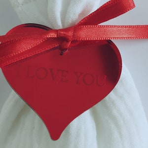 May include: A white fabric bag with a red ribbon and a red heart-shaped tag that says "Love You".