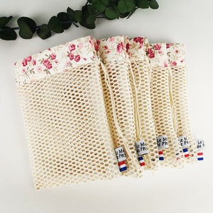 Puede incluir: Conjunto de seis bolsas de malla blanca para productos, con ribete de tela floral y cierre de cordón. Cada bolsa tiene una pequeña etiqueta con el texto "Le Marché de Ph", una bandera francesa y un pequeño corazón rojo.