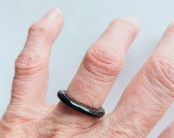 May include: A black ring worn on a finger.