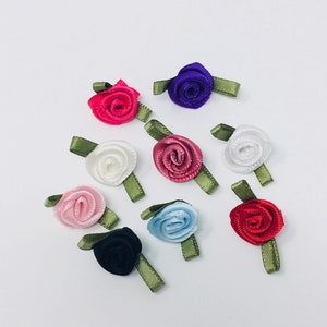 Könnte beinhalten: Sortiment von zehn kleinen Stoffrosen in verschiedenen Farben, darunter rosa, rot, weiß, blau, lila und schwarz. Jede Rose hat einen grünen Stiel.