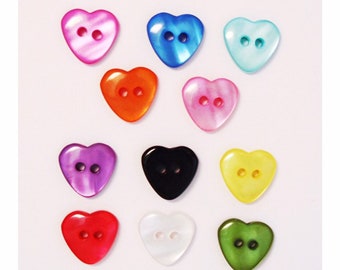 May include: Twelve heart-shaped buttons in various colours, including pink, blue, green, yellow, red, black, and white. Each button has two holes.