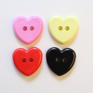 Può includere: Quattro bottoni a forma di cuore in rosa, giallo, rosso e nero. Ogni bottone ha due fori.