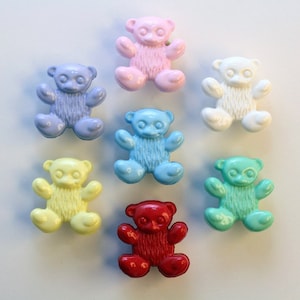 May include: Seven plastic teddy bear buttons in various colours: pink, light blue, white, yellow, blue, turquoise, and red.