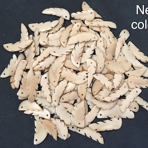 Puede incluir: Un montón de aproximadamente 50 colgantes en forma de pluma de color blanquecino, que parecen hueso. Los colgantes tienen dos agujeros en la parte superior para encordar.