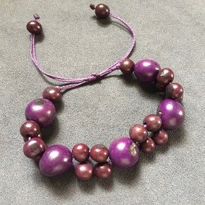 Peut inclure: Bracelet en perles de bois violet avec un cordon violet. Le bracelet a un nœud coulissant pour ajuster la taille.