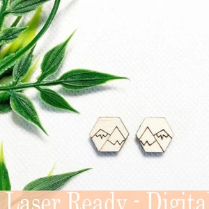 May include: Two wooden hexagon-shaped earrings with a mountain design. The earrings are light brown with a dark brown mountain outline. The image also includes green leaves and text that reads "Laser Ready - Digital File" and "Instant download SVG/DXF".