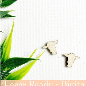 May include: Two small, light-colored cow head cutouts. The cow heads are positioned on a white background, with green and yellow leaves in the upper left corner. The text "Laser Ready - Digital File" and "Instant download SVG/DXF" is at the bottom.