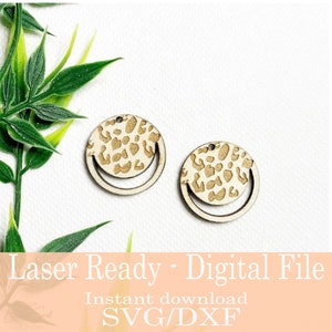 Op de afbeelding: Twee houten oorbellen met een luipaardprint ontwerp. Elke oorbel heeft een cirkelvormige bovenkant met een luipaardprint patroon en een lachend gezicht ontwerp eronder. De tekst "Laser Ready - Digital File" is onderaan zichtbaar.