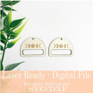 Op de afbeelding: Twee onafgewerkte houten oorbellen met een halve cirkel aan de bovenkant en een rechthoekige uitsparing. Elke oorbel heeft een gegraveerd maanfase-ontwerp. De afbeelding bevat ook de tekst "Laser Ready - Digital File" en "Instant download SVG/DXF".