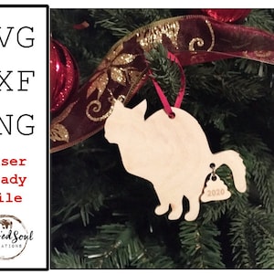 Op de afbeelding: Een houten katvormige kerstversiering die aan een boom hangt. De versiering heeft een belletje met het jaar "2020" gegraveerd. De afbeelding bevat de tekst "SVG, DXF, PNG, Laser Ready File" en het logo "Blessed Soul Creations".
