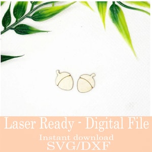 May include: Two small, light-coloured wooden acorn cutouts. The acorns have a simple, clean design with a cap and a detailed outline. The image includes text that reads "Laser Ready - Digital File" and "Instant download SVG/DXF".