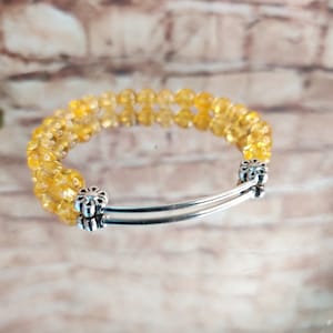 Peut inclure: Un bracelet à double rang de perles de citrine jaune et d'accents en métal argenté. Le bracelet a un design simple et élégant, parfait pour tous les jours.
