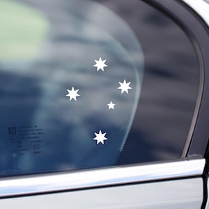 Könnte beinhalten: Ein weißes Autofenster mit einem Aufkleber der Kreuz des Südens Konstellation, eine Gruppe von fünf weißen Sternen auf einem dunkelblauen Hintergrund.