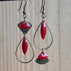 Puede incluir: Un par de pendientes colgantes con detalles rojos y dorados. Los pendientes tienen forma de lágrima con una lágrima más pequeña y una pieza en forma de abanico que cuelga de ella. Los pendientes son de metal y tienen un aspecto vintage.