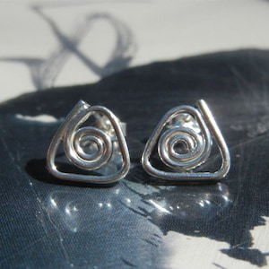 May include: A pair of silver earrings with a spiral design. The earrings are shaped like triangles.