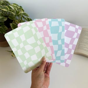 May include: A set of three ceramic mugs with a speckled, matte finish. Each mug features a different color: light blue, cream, and gray. The mugs have a simple, modern design and a comfortable handle.