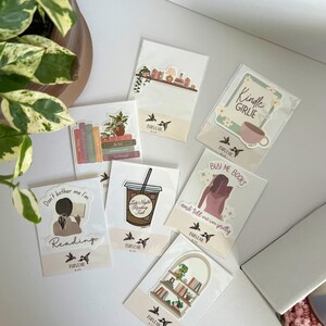 May include: A collection of stickers with various designs, including a coffee cup, a bookshelf, and the text "Kindle Girlie." The stickers feature illustrations and text related to reading and books. The brand name "Birdie & Co" is visible on the stickers.