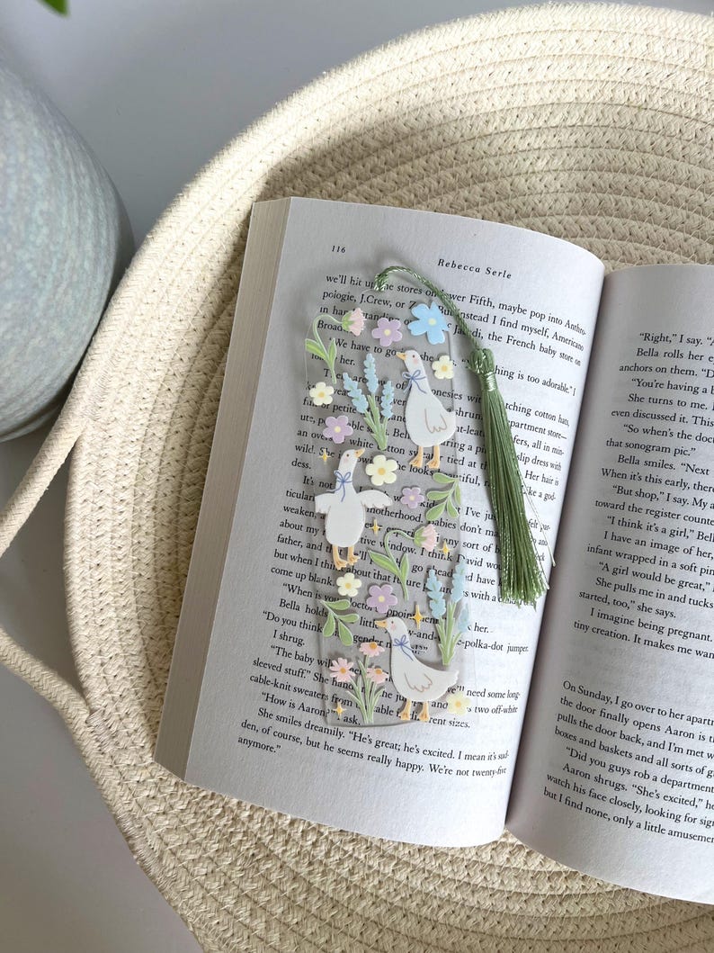 May include: A clear bookmark with a floral design and three white ducks. The bookmark has a green tassel and the text "Right" and "Bella rolls her eyes" is visible.