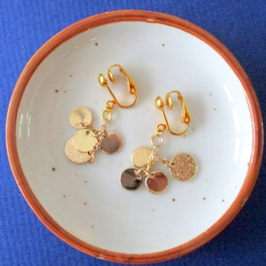 Clip earrings four small golden pucks hanging from a chain