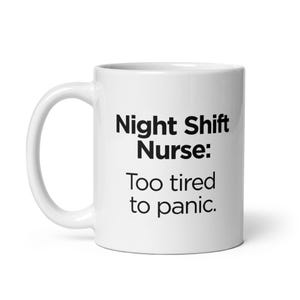 May include: White ceramic mug with a curved handle. The mug features the text "Night Shift Nurse: Too tired to panic" in black, bold font. A practical and humorous gift for nurses.